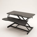 Sit-stand desk converter raised to mid height, showing the upper platform, keyboard tray and scissor lift