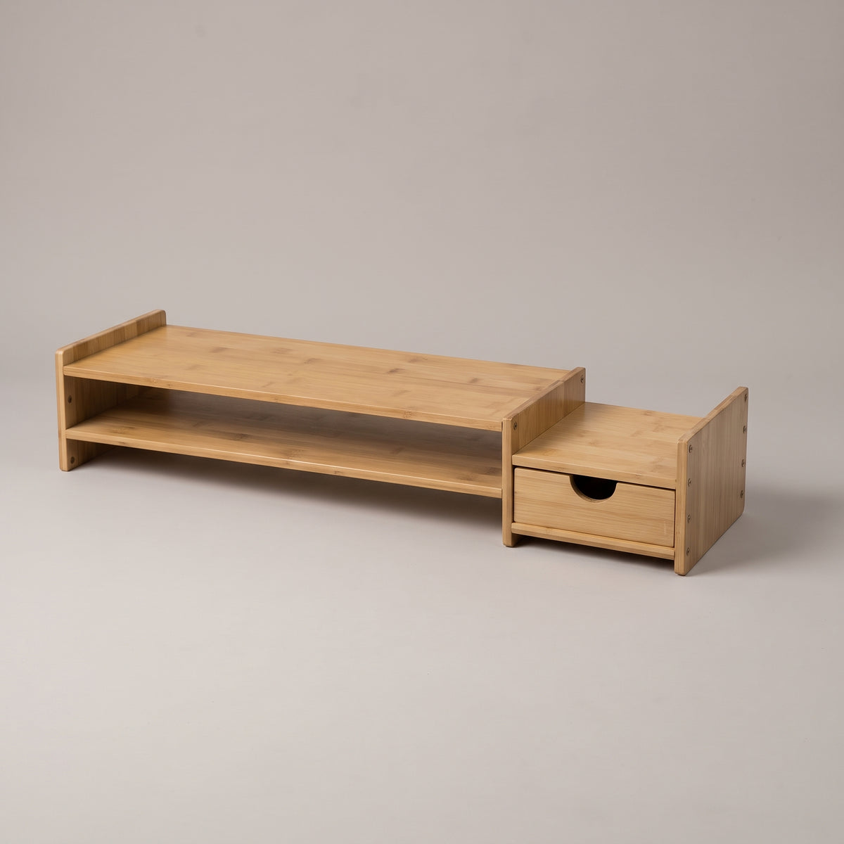 Bamboo monitor stand with a full-width lower shelf and a pull-out drawer at one end