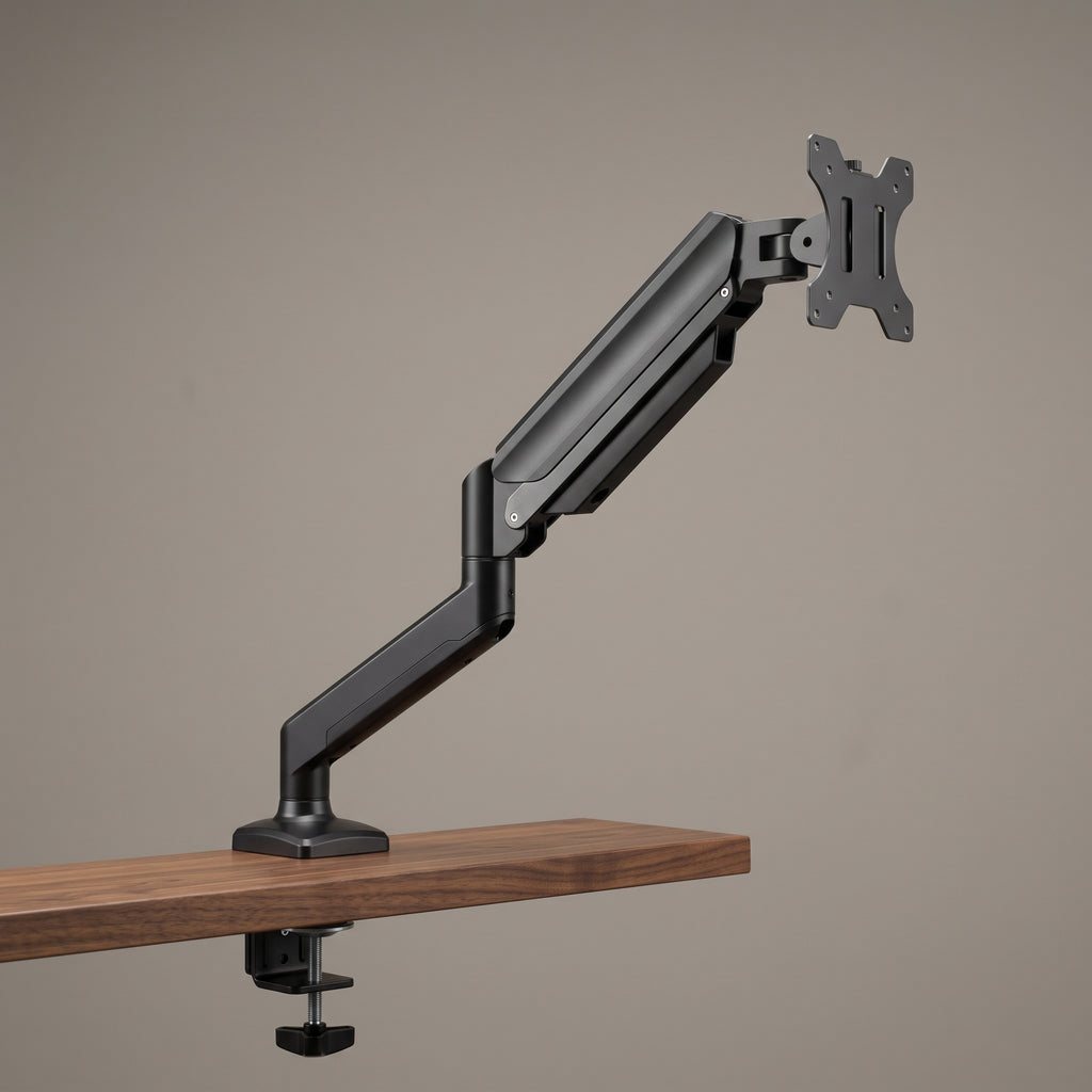 Gas spring monitor arm clamped to a walnut desk, holding a single monitor at eye height