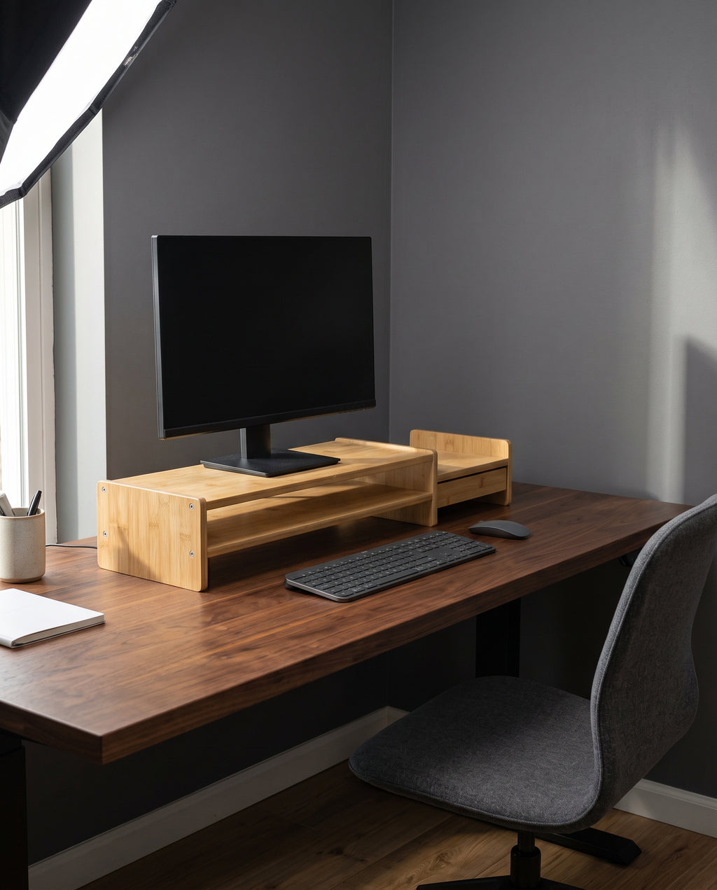 Bamboo monitor stand in use on a desk, raising the monitor above the keyboard