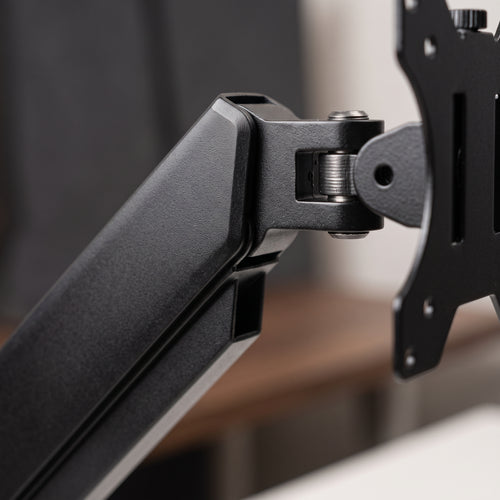 Close-up of the gas spring monitor arm segments and the VESA mounting head