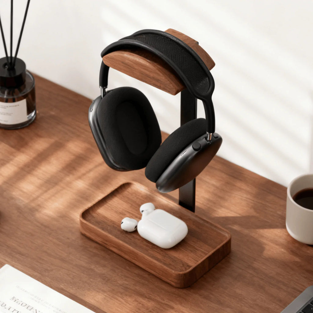 Walnut headphone stand holding over-ear headphones, with earbuds resting in the base tray